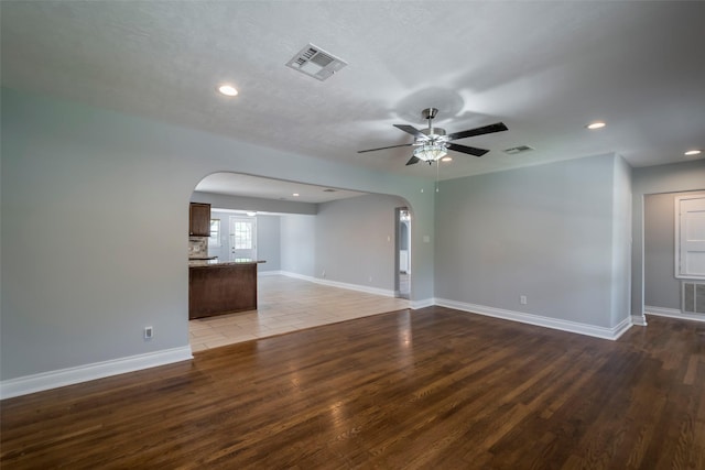 1109 Dismuke St, Houston, TX 77023 - unfurnished living room featuring arched walkways, wood finished floors, recessed lighting, ceiling fan, and baseboards