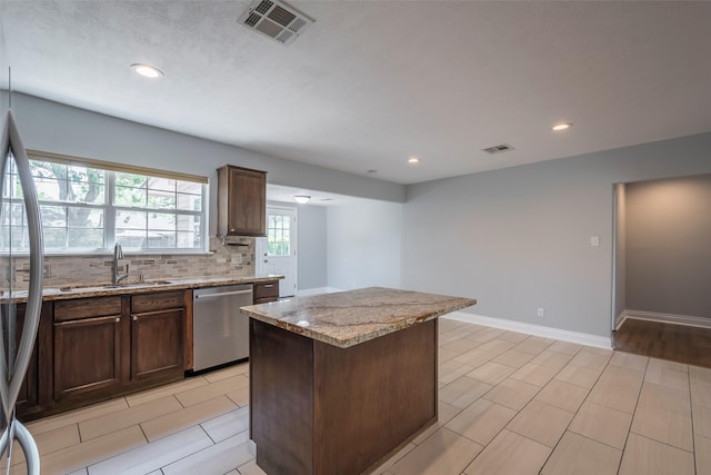 1109 Dismuke St, Houston, TX 77023 - kitchen featuring stainless steel appliances, a sink, light stone countertops, tasteful backsplash, and a kitchen island