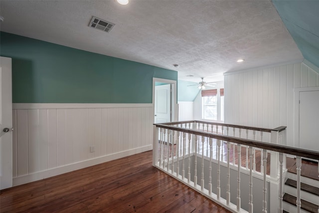 1109 Dismuke St, Houston, TX 77023 - hall featuring hardwood / wood-style flooring, a textured ceiling, wainscoting, baseboards, and an upstairs landing