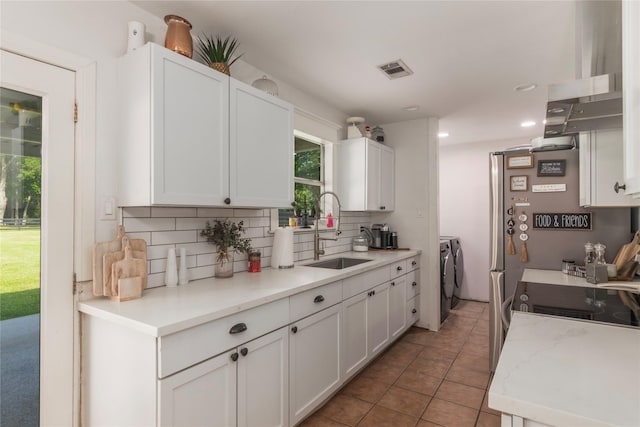 79 E Pine Dr, Huffman, TX 77336 - kitchen with washing machine and clothes dryer, a sink, backsplash, white cabinets, and light tile patterned floors