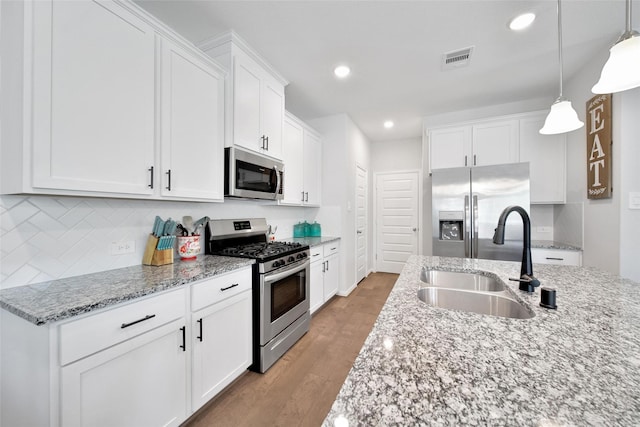103 Skyshine Ct, Conroe, TX 77304 - kitchen with appliances with stainless steel finishes, a sink, recessed lighting, light stone counters, and white cabinetry