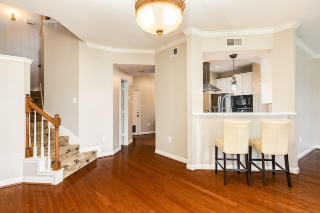 458 Mariners Dr, Kemah, TX 77565 - kitchen featuring black microwave, wood finished floors, wall chimney exhaust hood, baseboards, and ornamental molding