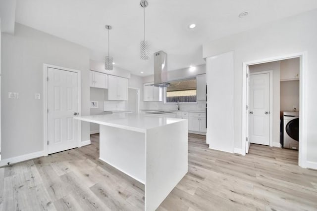 7607 Bankside Dr, Houston, TX 77071 - kitchen featuring washer / dryer, island range hood, white cabinetry, light countertops, and light wood finished floors
