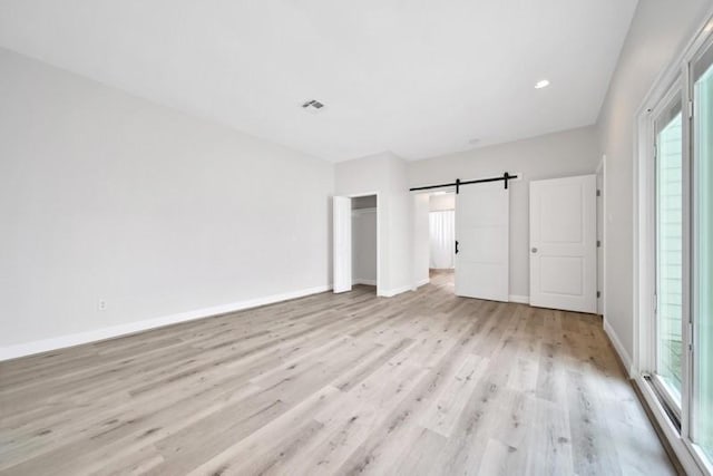 7607 Bankside Dr, Houston, TX 77071 - unfurnished bedroom with a barn door, multiple windows, light wood-type flooring, baseboards, and recessed lighting