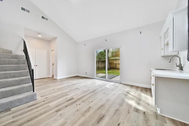 7607 Bankside Dr, Houston, TX 77071 - unfurnished living room featuring high vaulted ceiling, a sink, stairway, light wood-style floors, and baseboards