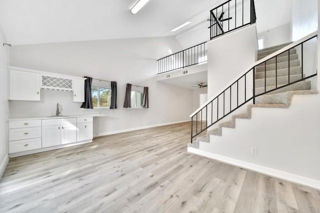 7607 Bankside Dr, Houston, TX 77071 - unfurnished living room with high vaulted ceiling, stairway, light wood finished floors, a sink, and baseboards
