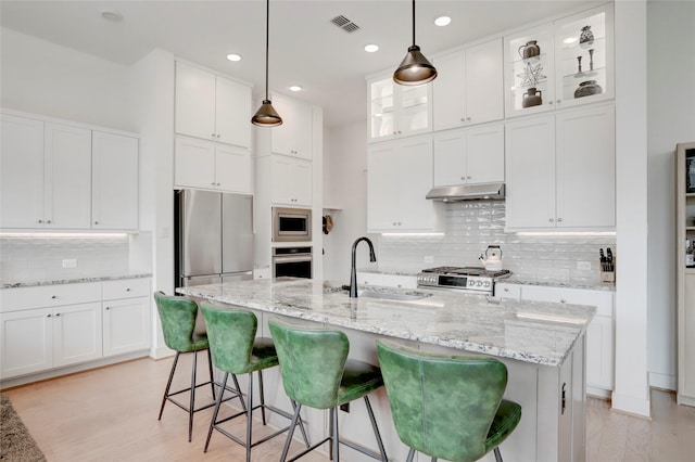 3124 Somerset Levens Ln, Houston, TX 77055 - kitchen featuring a sink, under cabinet range hood, appliances with stainless steel finishes, tasteful backsplash, and a kitchen breakfast bar