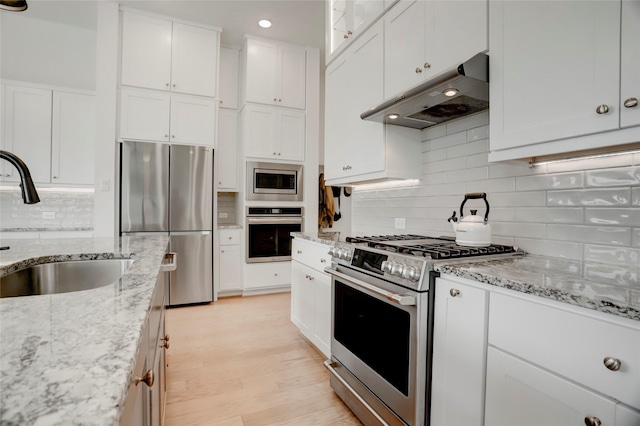 3124 Somerset Levens Ln, Houston, TX 77055 - kitchen with appliances with stainless steel finishes, under cabinet range hood, a sink, white cabinetry, and backsplash