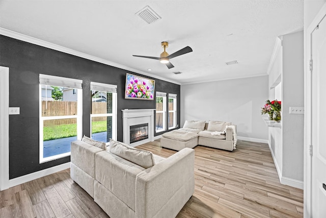 5702 W Vistaglen Loop, Houston, TX 77084 - living area featuring crown molding, baseboards, light wood finished floors, a glass covered fireplace, and a ceiling fan