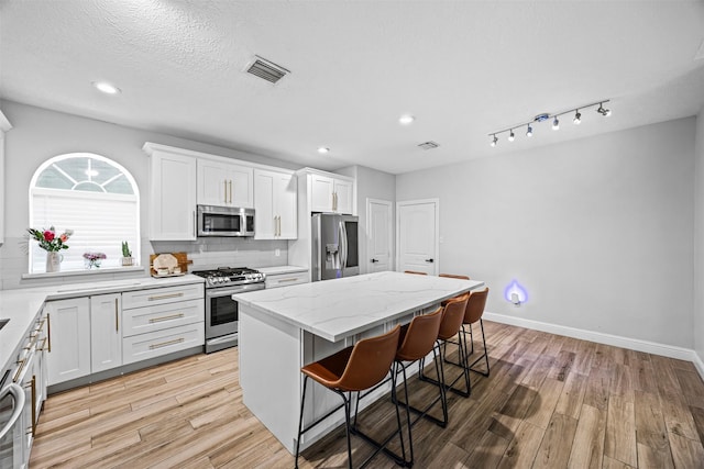 5702 W Vistaglen Loop, Houston, TX 77084 - kitchen with appliances with stainless steel finishes, a breakfast bar area, light wood finished floors, a center island, and recessed lighting