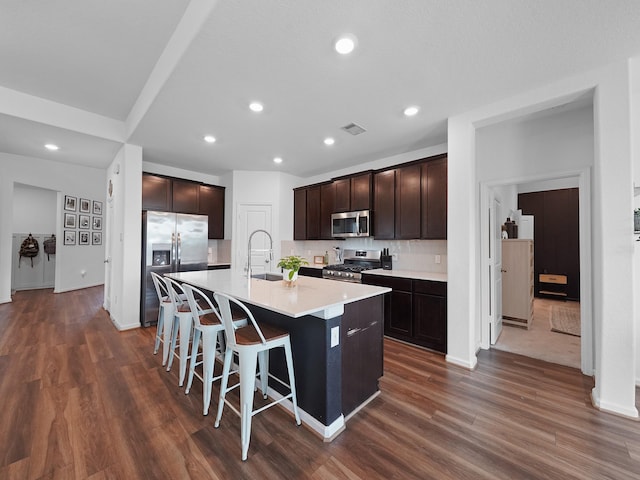 18925 Lazzaro Springs Dr, New Caney, TX 77357 - kitchen featuring stainless steel appliances, a center island with sink, a breakfast bar, a sink, and dark brown cabinetry