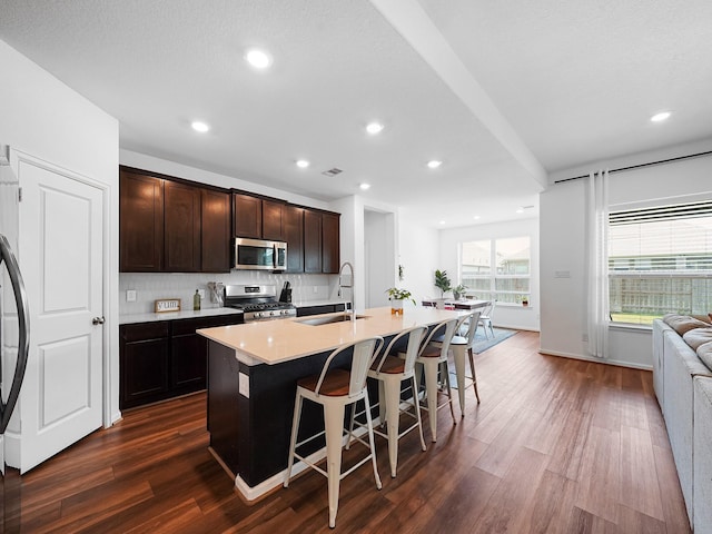 18925 Lazzaro Springs Dr, New Caney, TX 77357 - kitchen featuring appliances with stainless steel finishes, a sink, dark wood-style floors, a breakfast bar, and recessed lighting