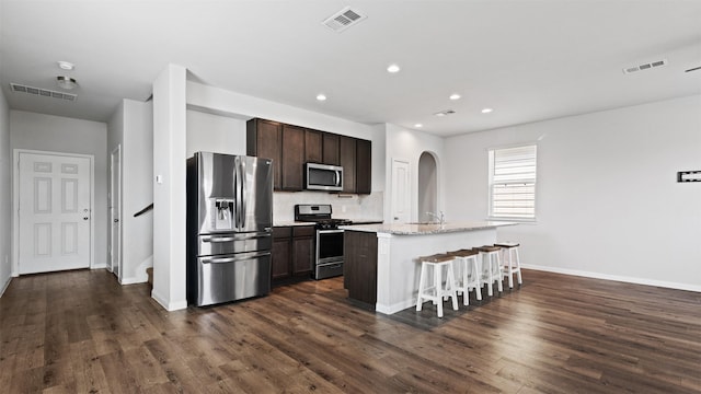 22002 Sovereign Heights Ln, Houston, TX 77073 - kitchen with appliances with stainless steel finishes, arched walkways, dark brown cabinetry, dark wood finished floors, and recessed lighting