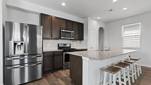 22002 Sovereign Heights Ln, Houston, TX 77073 - kitchen with stainless steel appliances, arched walkways, dark brown cabinets, dark wood finished floors, and recessed lighting