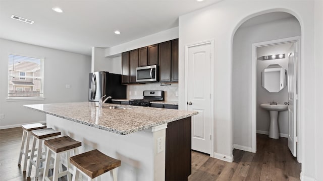 22002 Sovereign Heights Ln, Houston, TX 77073 - kitchen with stainless steel appliances, a sink, a kitchen bar, baseboards, and dark brown cabinetry