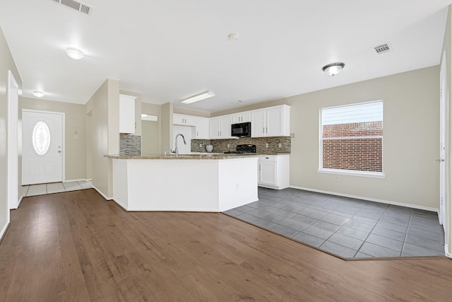 4814 Winding Timbers Ct, Humble, TX 77346 - kitchen with black microwave, stove, dark wood-type flooring, and tasteful backsplash