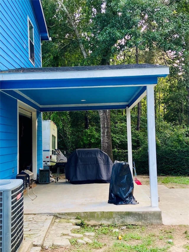 195 Rim Rock Rd, Onalaska, TX 77360 - view of patio / terrace with central AC, a carport, and view of wooded area