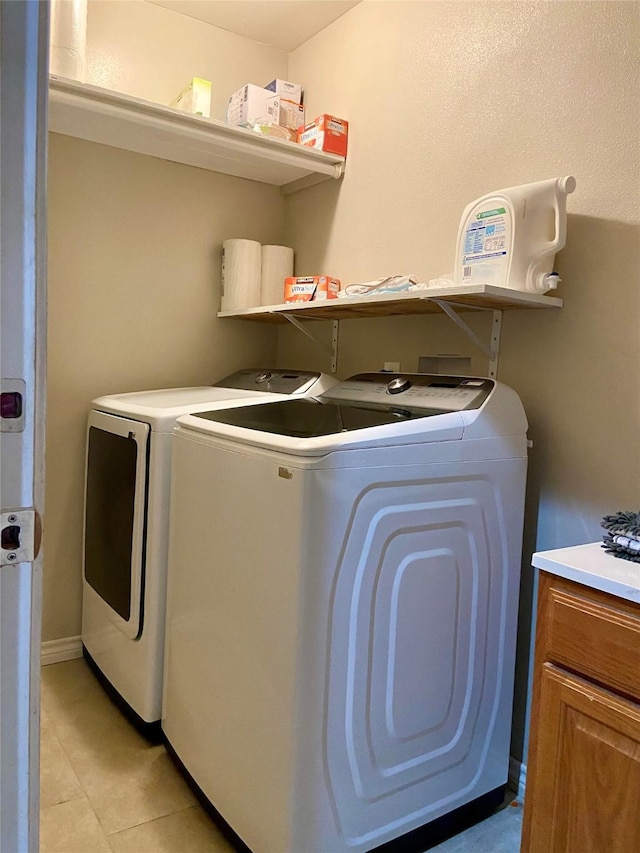 195 Rim Rock Rd, Onalaska, TX 77360 - laundry room featuring washer and clothes dryer, light tile patterned floors, and cabinet space