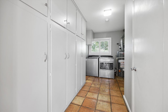 7222 Hartland Ave, Houston, TX 77055 - laundry room featuring separate washer and dryer, cabinet space, water heater, stone tile floors, and baseboards