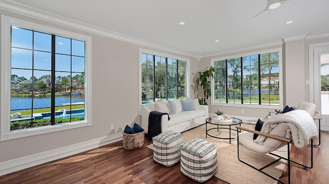 living area with wood finished floors, crown molding, plenty of natural light, baseboards, and a water view