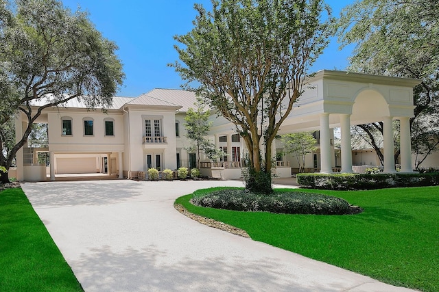 view of front of house featuring stucco siding, curved driveway, a front lawn, french doors, and a standing seam roof