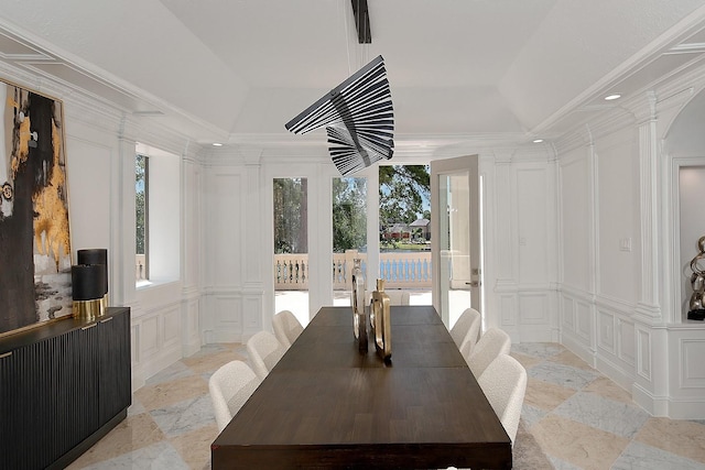 dining area with a decorative wall, stone tile floors, healthy amount of natural light, and ornate columns