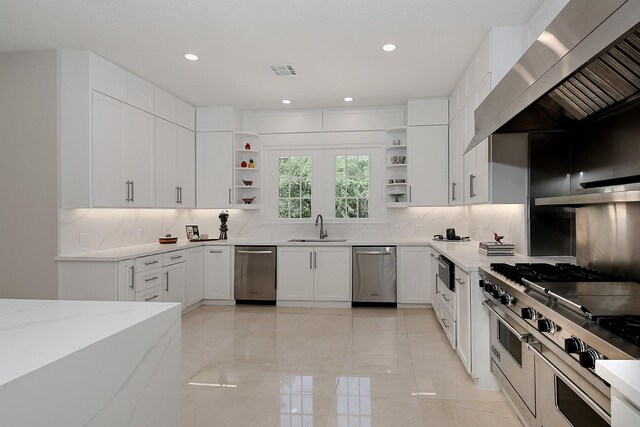 kitchen featuring open shelves, appliances with stainless steel finishes, a sink, wall chimney range hood, and decorative backsplash