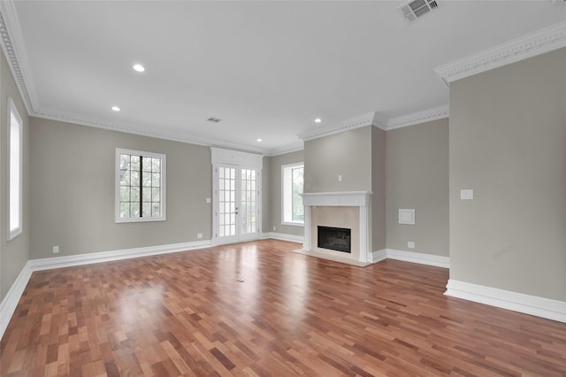 unfurnished living room featuring plenty of natural light, wood finished floors, baseboards, crown molding, and recessed lighting