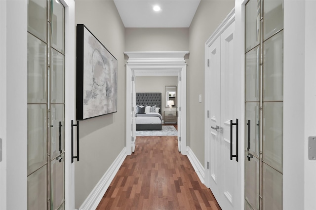 corridor featuring dark wood-type flooring and baseboards