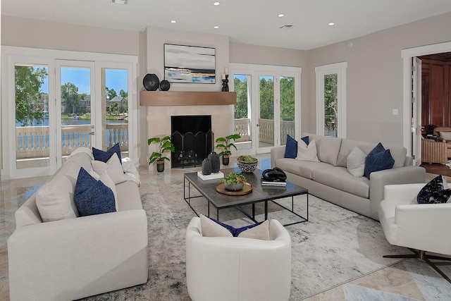 living room with recessed lighting, a fireplace, and a water view