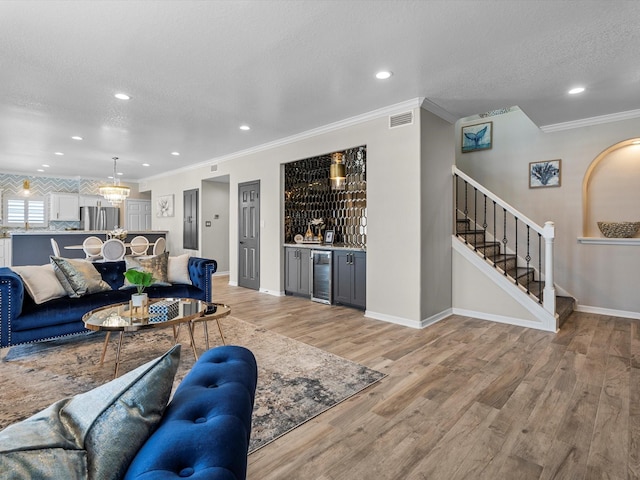 441 Jeanie Lynn St, Galveston, TX 77554 - living area with beverage cooler, a dry bar, crown molding, stairway, and light wood-style floors