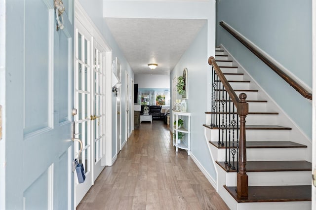 9519 Territory Ln, Houston, TX 77064 - foyer with stairs, light wood-type flooring, a textured ceiling, and baseboards