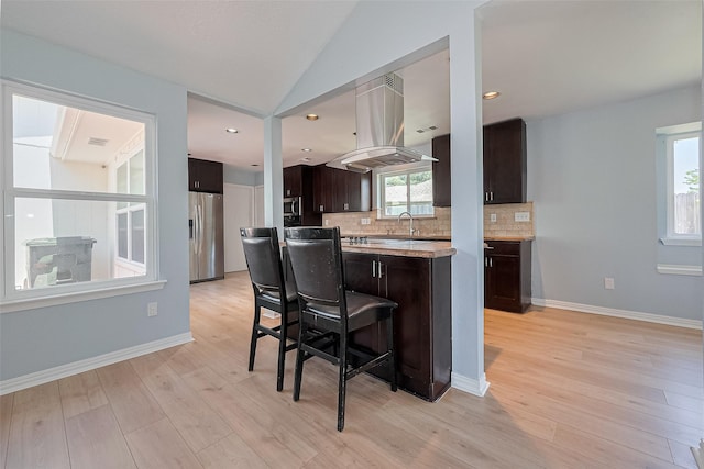 12703 Fenimore Ct, Sugar Land, TX 77478 - kitchen featuring island range hood, stainless steel appliances, dark brown cabinets, light countertops, and tasteful backsplash