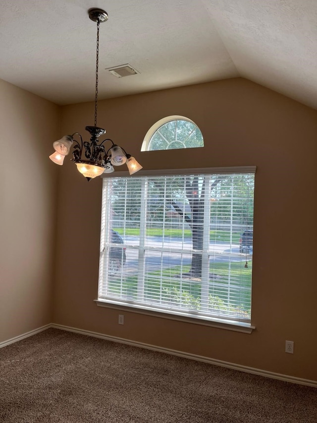 carpeted empty room with a chandelier, vaulted ceiling, and baseboards