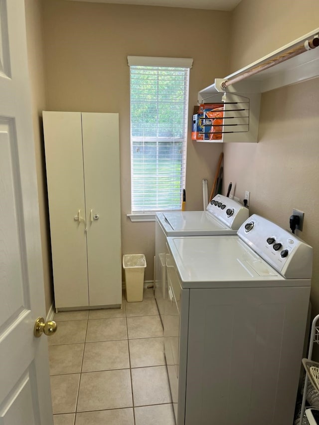 laundry room with washing machine and dryer, light tile patterned floors, cabinet space, and baseboards