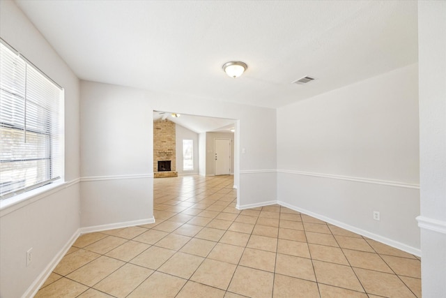 5519 Fallengate Dr, Spring, TX 77373 - unfurnished room with light tile patterned floors, baseboards, a brick fireplace, and vaulted ceiling