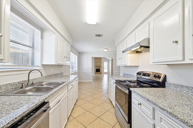 5519 Fallengate Dr, Spring, TX 77373 - kitchen with appliances with stainless steel finishes, under cabinet range hood, a sink, white cabinetry, and light tile patterned floors