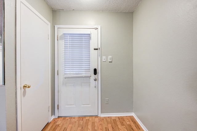 8229 Kingsbrook Rd Unit 229, Houston, TX 77024 - doorway with light wood-style flooring, baseboards, and a textured ceiling