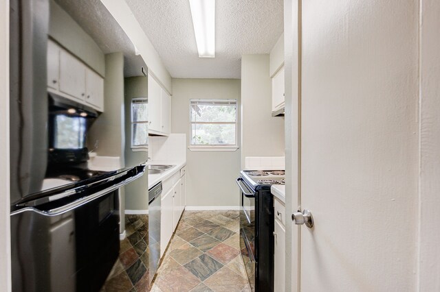 8229 Kingsbrook Rd Unit 229, Houston, TX 77024 - kitchen featuring black range with electric cooktop, stone finish floors, fridge, white cabinets, and a textured ceiling