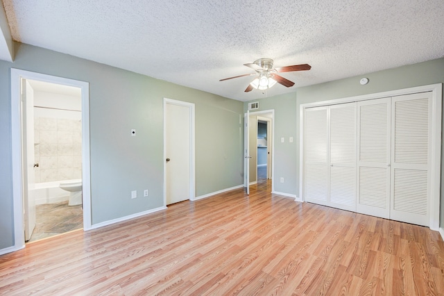 8229 Kingsbrook Rd Unit 229, Houston, TX 77024 - unfurnished bedroom with light wood-style flooring, a textured ceiling, ensuite bathroom, a closet, and baseboards