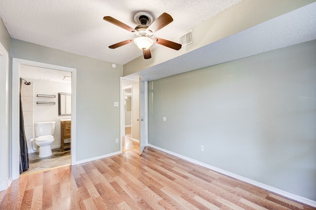 8229 Kingsbrook Rd Unit 229, Houston, TX 77024 - unfurnished bedroom featuring a textured ceiling, light wood-style floors, connected bathroom, baseboards, and ceiling fan