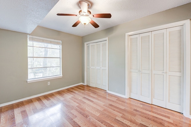 8229 Kingsbrook Rd Unit 229, Houston, TX 77024 - unfurnished bedroom with light wood finished floors, baseboards, multiple closets, a textured ceiling, and ceiling fan
