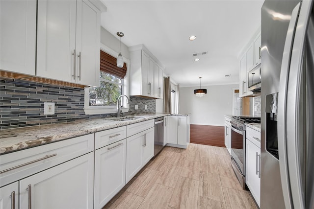 5322 Windswept Ln, Houston, TX 77056 - kitchen featuring appliances with stainless steel finishes, a sink, white cabinets, backsplash, and pendant lighting