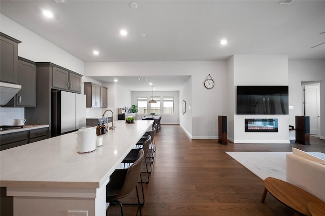 1682 Sherwood Glen Dr, Friendswood, TX 77546 - kitchen with freestanding refrigerator, open floor plan, a kitchen bar, a large island, and dark wood-style flooring