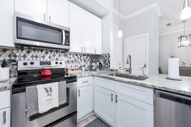 300 St Joseph Pkwy Unit 121, Houston, TX 77002 - kitchen featuring appliances with stainless steel finishes, a sink, crown molding, white cabinetry, and decorative backsplash