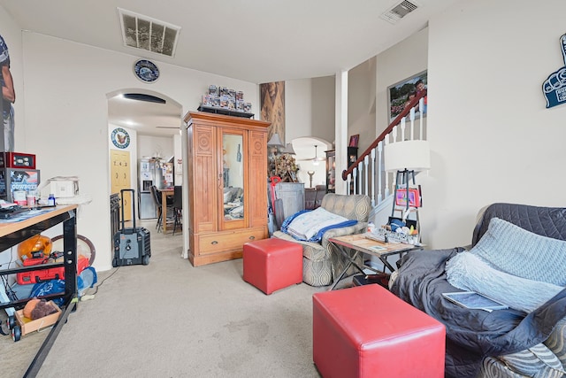 sitting room with arched walkways, carpet floors, and stairway