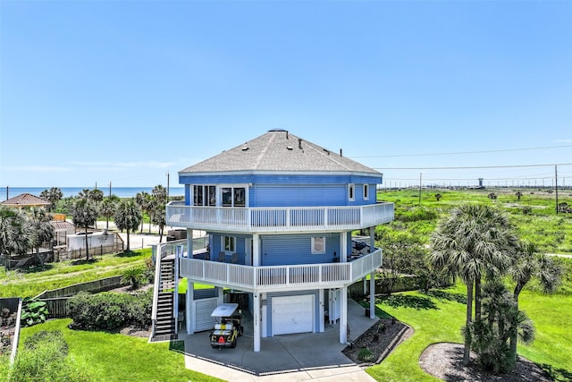 rear view of house featuring a balcony, an attached garage, stairway, a shingled roof, and concrete driveway