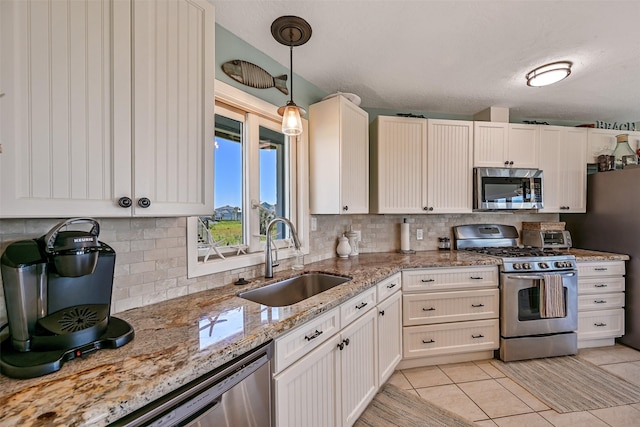 kitchen with stainless steel appliances, a sink, decorative backsplash, and pendant lighting