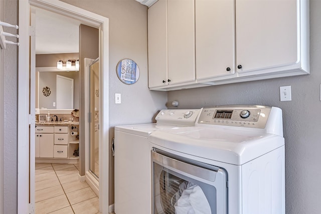laundry area featuring washing machine and dryer, light tile patterned floors, and cabinet space