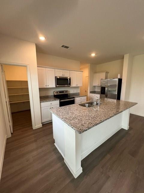 21596 Rolling Streams Dr, New Caney, TX 77357 - kitchen featuring appliances with stainless steel finishes, a sink, dark wood finished floors, white cabinetry, and a large island with sink